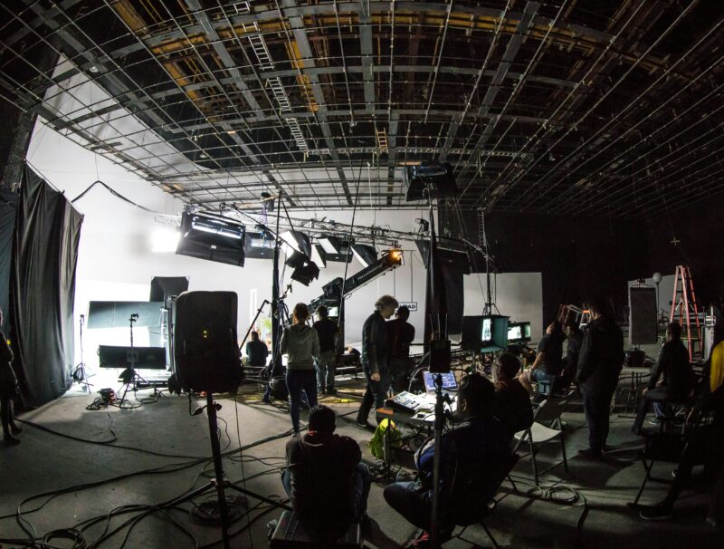 In a large television studio, a crew is gathered to film a video.